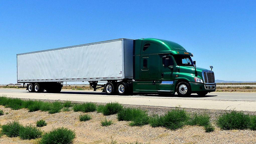 Texas Top Notch Trucking green and white full load truck driving down highway